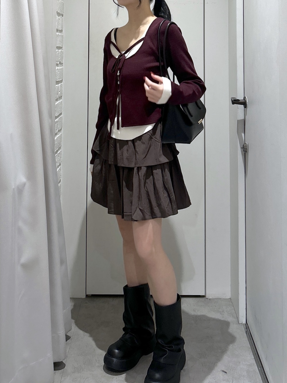 ブラウン系のスカート、ブラック系のショルダーバッグを着用したレディースの冬コーディネートの1枚目の写真