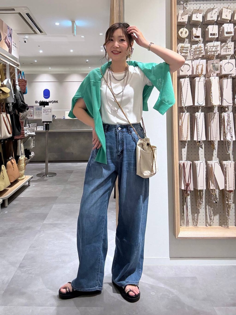ブルー系のデニムパンツ、グリーン系のカーディガン/ボレロ、ベージュ系のボディバッグ/ウエストポーチを着用したレディースの夏コーディネートの1枚目の写真
