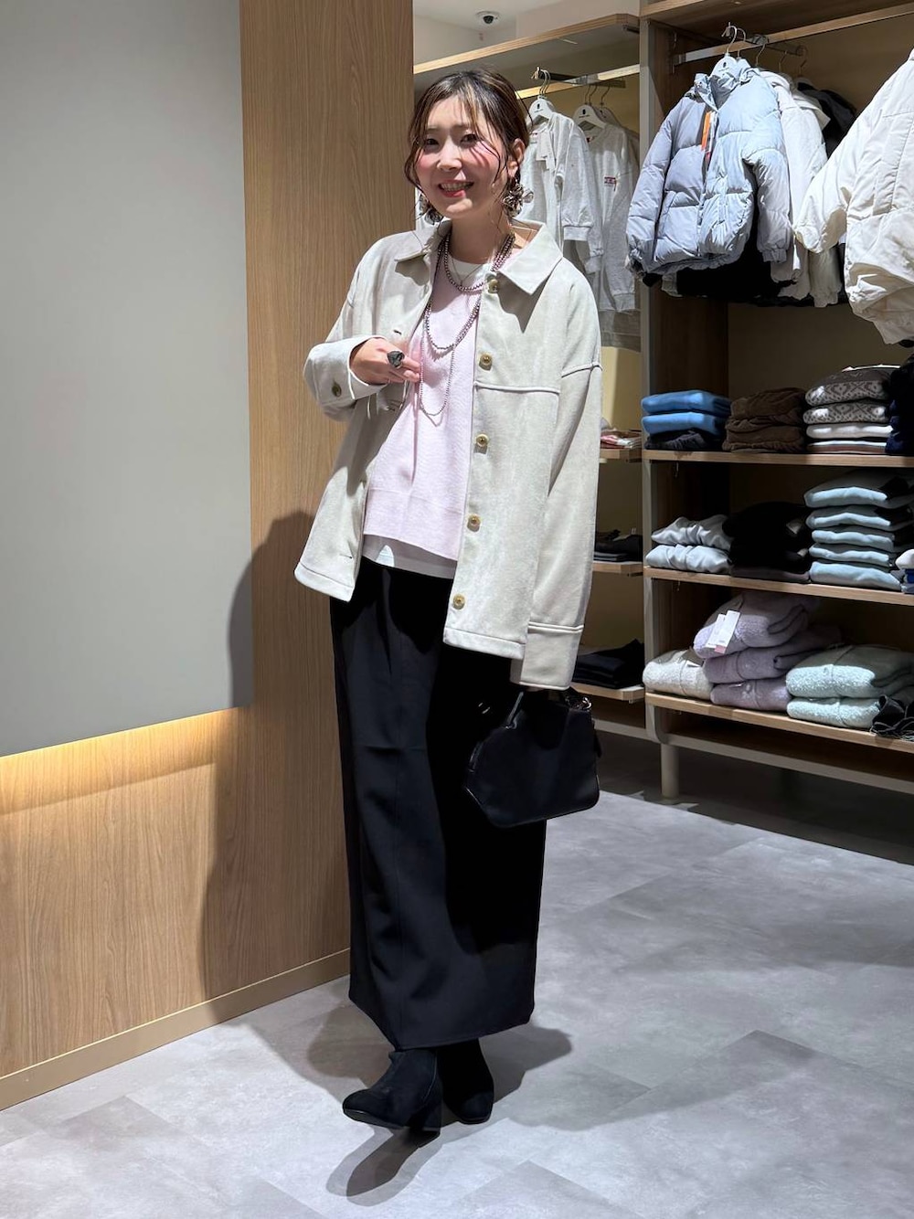 ブラック系のショルダーバッグ、ホワイト系のTシャツ/カットソー、ブラック系のブーツを着用したレディースの冬コーディネートの1枚目の写真