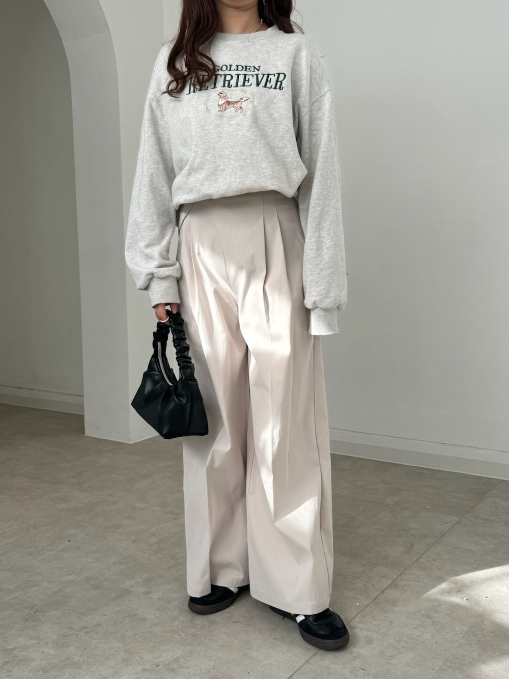 ホワイト系のスウェット、ホワイト系のスラックス、ブラック系のバッグを着用したレディースの春コーディネートの1枚目の写真