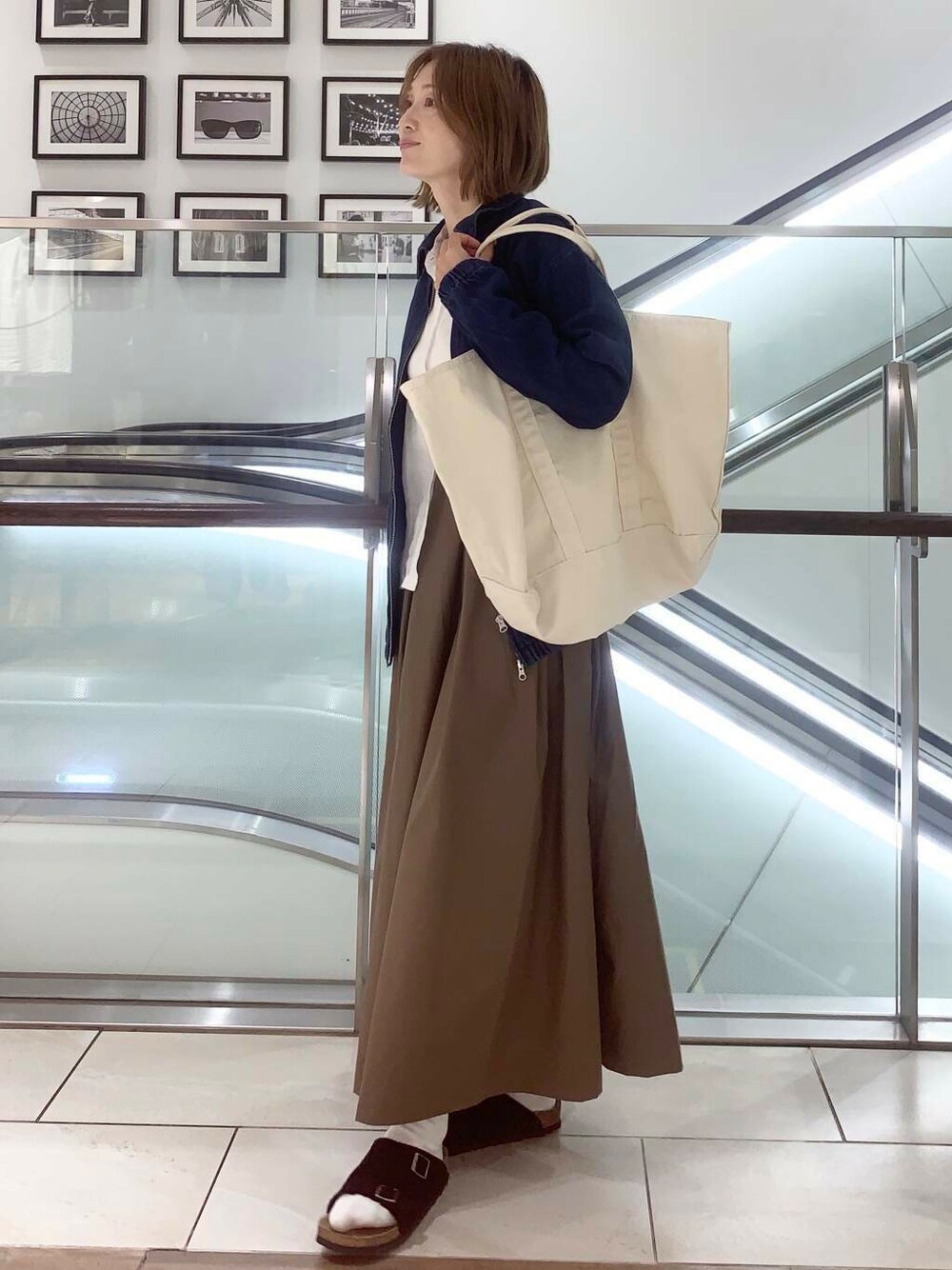 ホワイト系のトートバッグ、ブルー系のデニムジャケット、ホワイト系のシャツ/ブラウスを着用したレディースの夏コーディネートの1枚目の写真