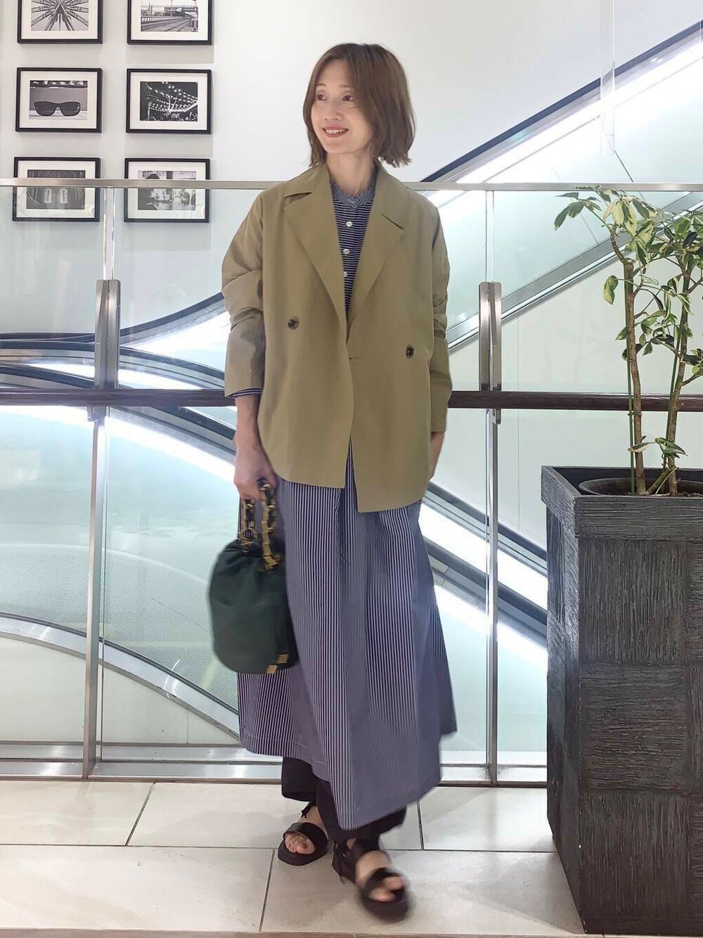 ブラック系のサンダル、グリーン系のショルダーバッグ、ブルー系のワンピースを着用したレディースの夏コーディネートの1枚目の写真