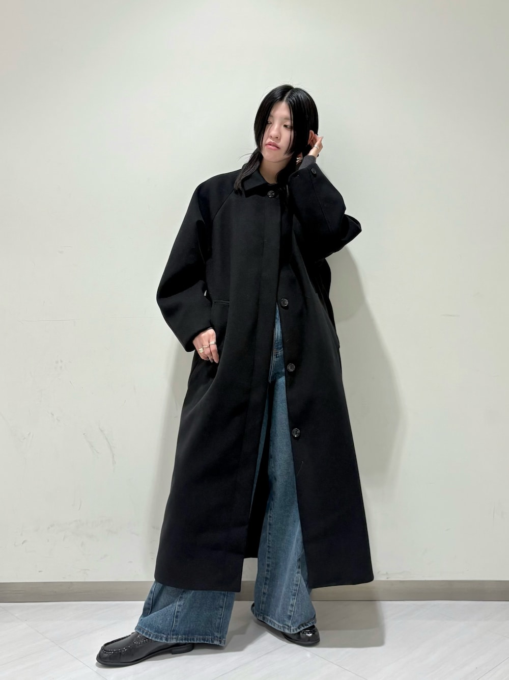 ブラック系のステンカラーコート、ブルー系のデニムパンツ、ブラック系のその他シューズを着用したレディースの秋コーディネートの1枚目の写真