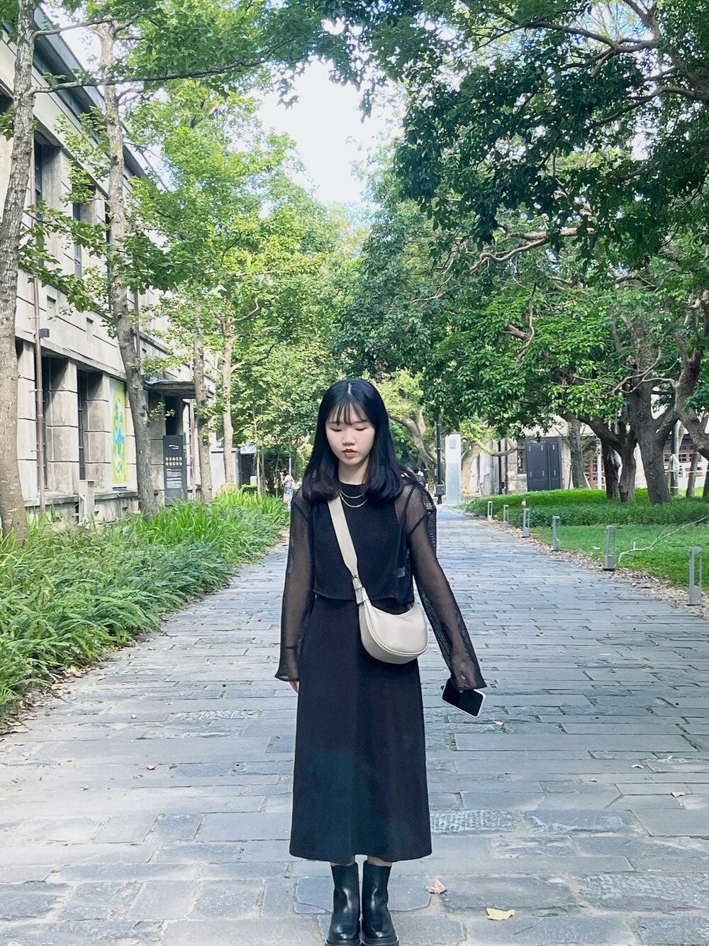 ブラック系のジャンパースカート、グレー系のボディバッグ/ウエストポーチ、ブラック系のブーツを着用したレディースの春コーディネートの1枚目の写真