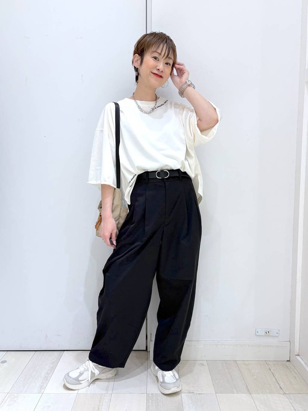 ブラック系のその他パンツ、ベージュ系のTシャツ/カットソー、ホワイト系のスニーカーを着用したレディースの春コーディネートの1枚目の写真