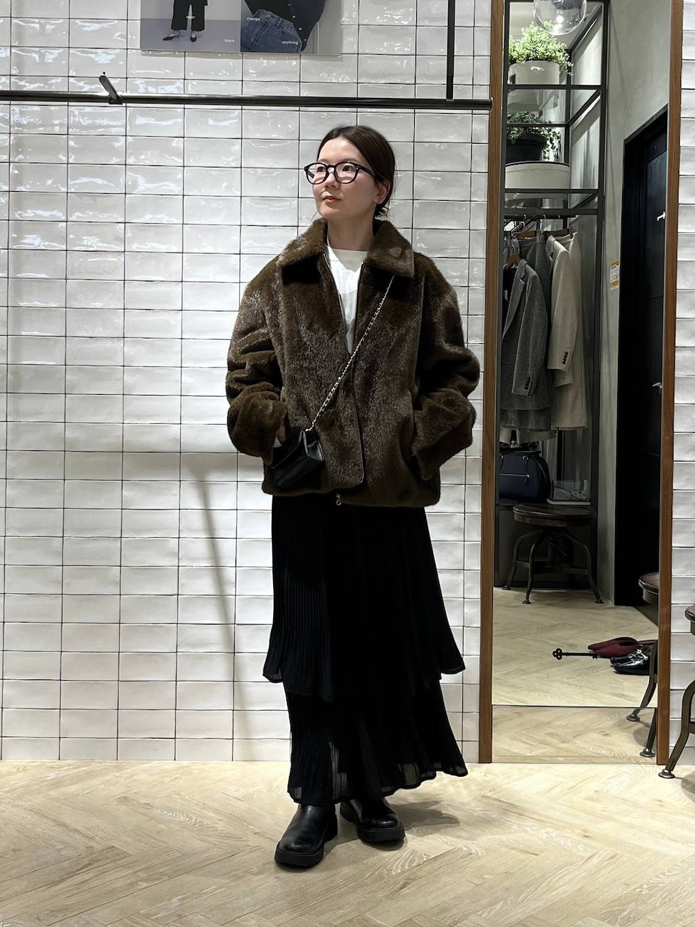 ブラック系のブーツ、ブラック系のスカート、ホワイト系のTシャツ/カットソーを着用したレディースの秋コーディネートの1枚目の写真