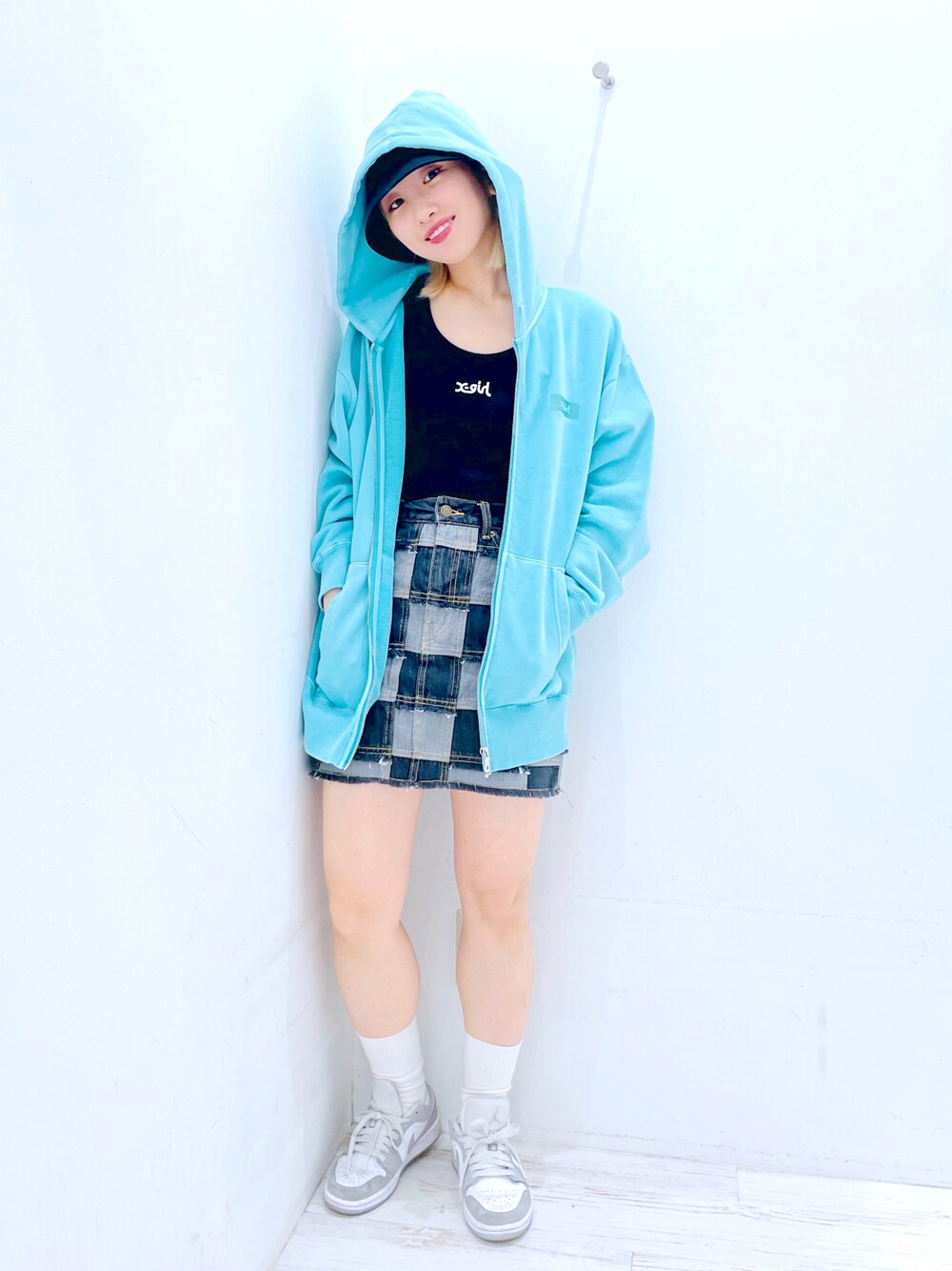 ブラック系のデニムスカート、レッド系のタンクトップ、グリーン系のパーカーを着用したレディースの春コーディネートの1枚目の写真