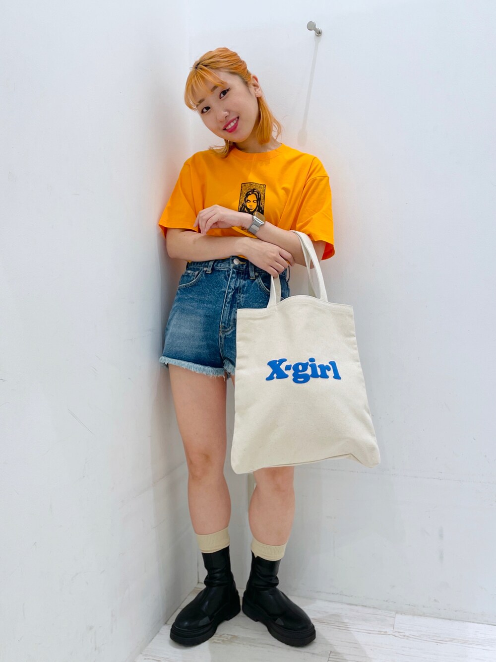 ホワイト系のトートバッグ、ブルー系のその他パンツ、オレンジ系のTシャツ/カットソーを着用したレディースの夏コーディネートの1枚目の写真