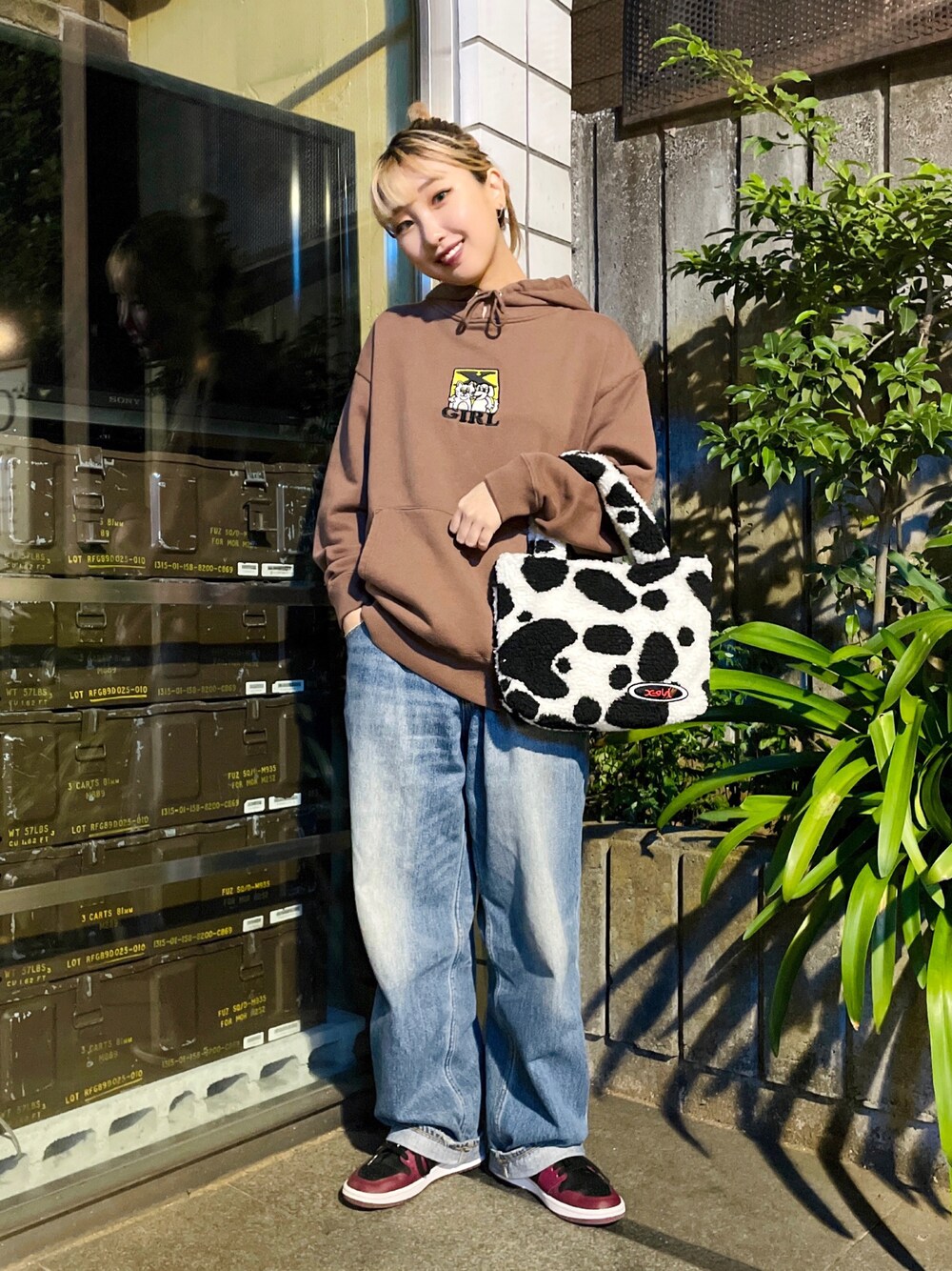 ブラウン系のパーカー、ホワイト系のトートバッグ、ブルー系のデニムパンツを着用したレディースの秋コーディネートの1枚目の写真