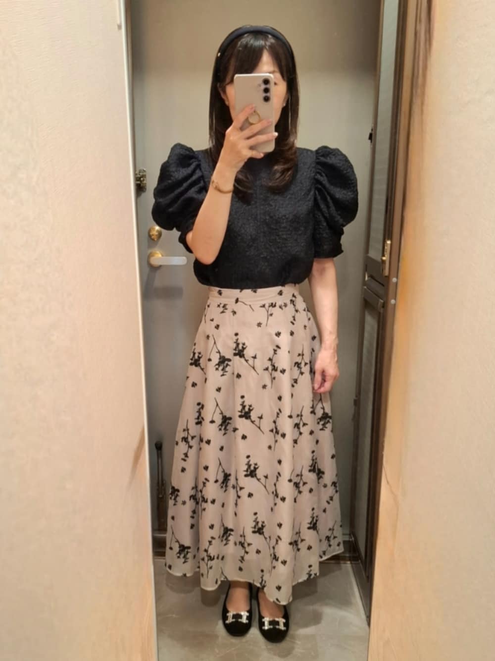 ベージュ系のスカート、ホワイト系のシャツ/ブラウス、ブラック系のパンプスを着用したレディースの夏コーディネートの1枚目の写真