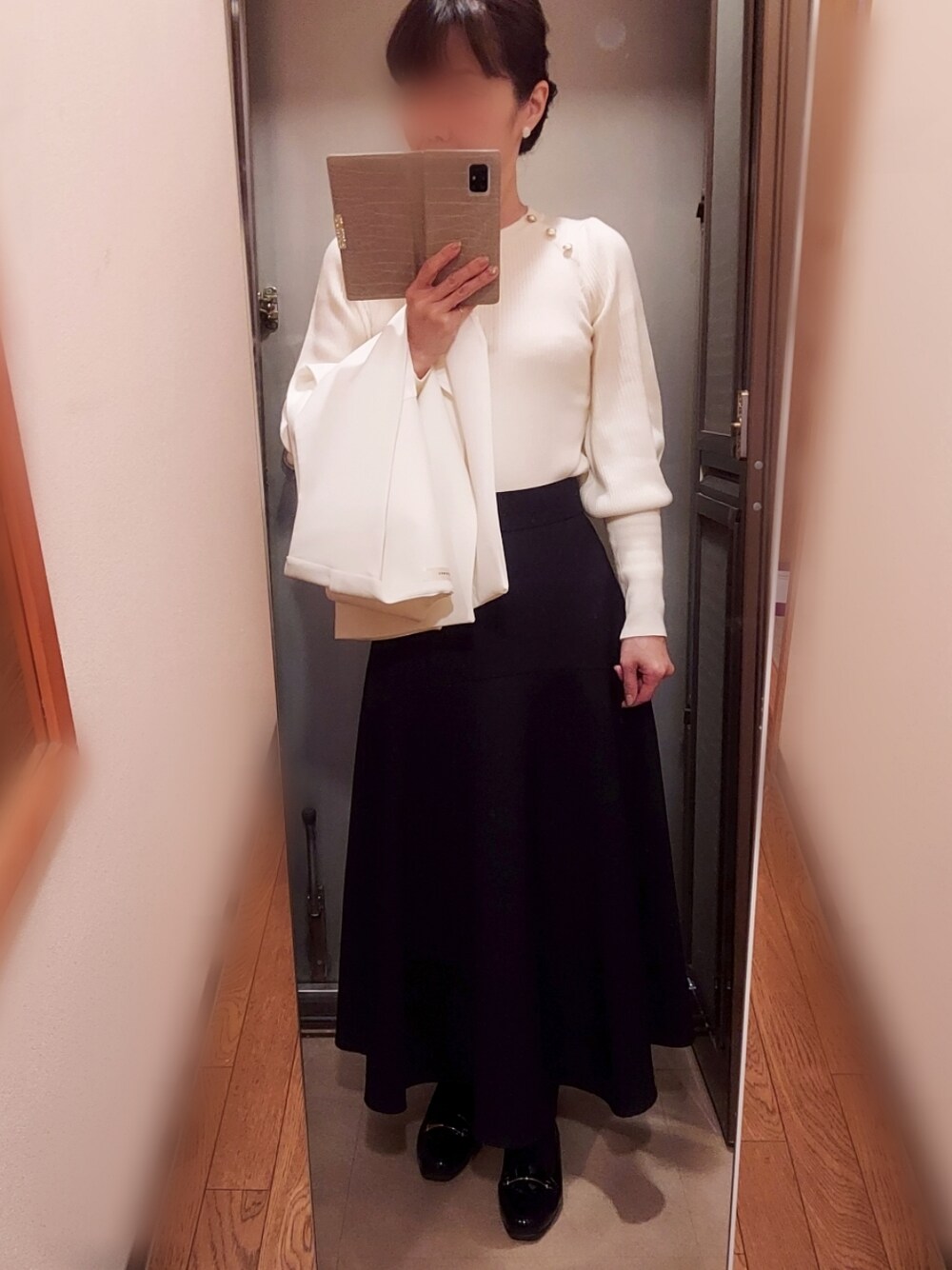 ブラック系のスカート、ブラック系のローファー、ホワイト系のニット/セーターを着用したレディースの春コーディネートの2枚目の写真