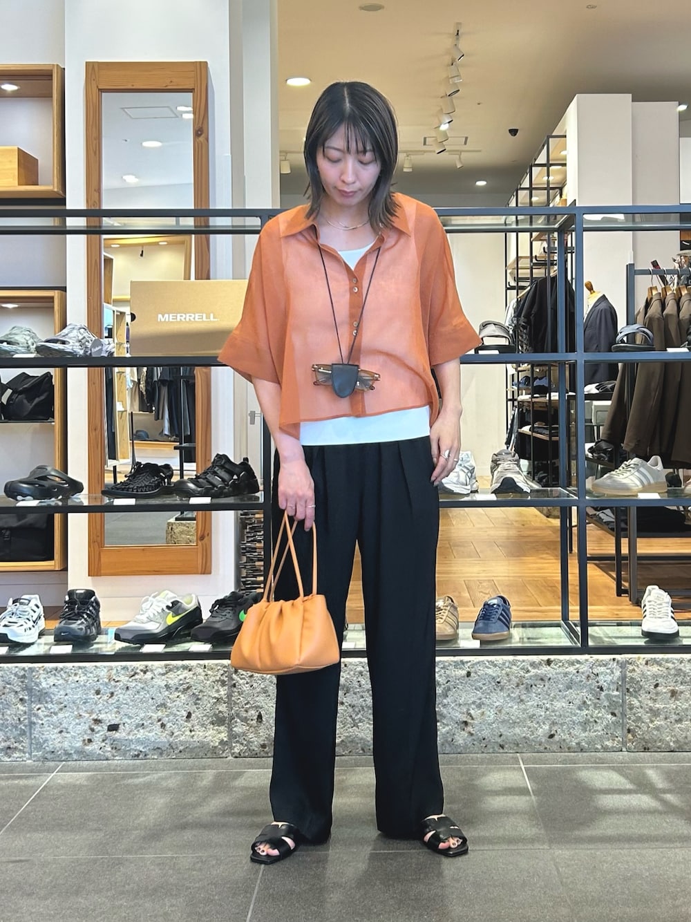 ブラック系のその他パンツ、ブラック系のサンダル、オレンジ系のショルダーバッグを着用したレディースの春コーディネートの1枚目の写真