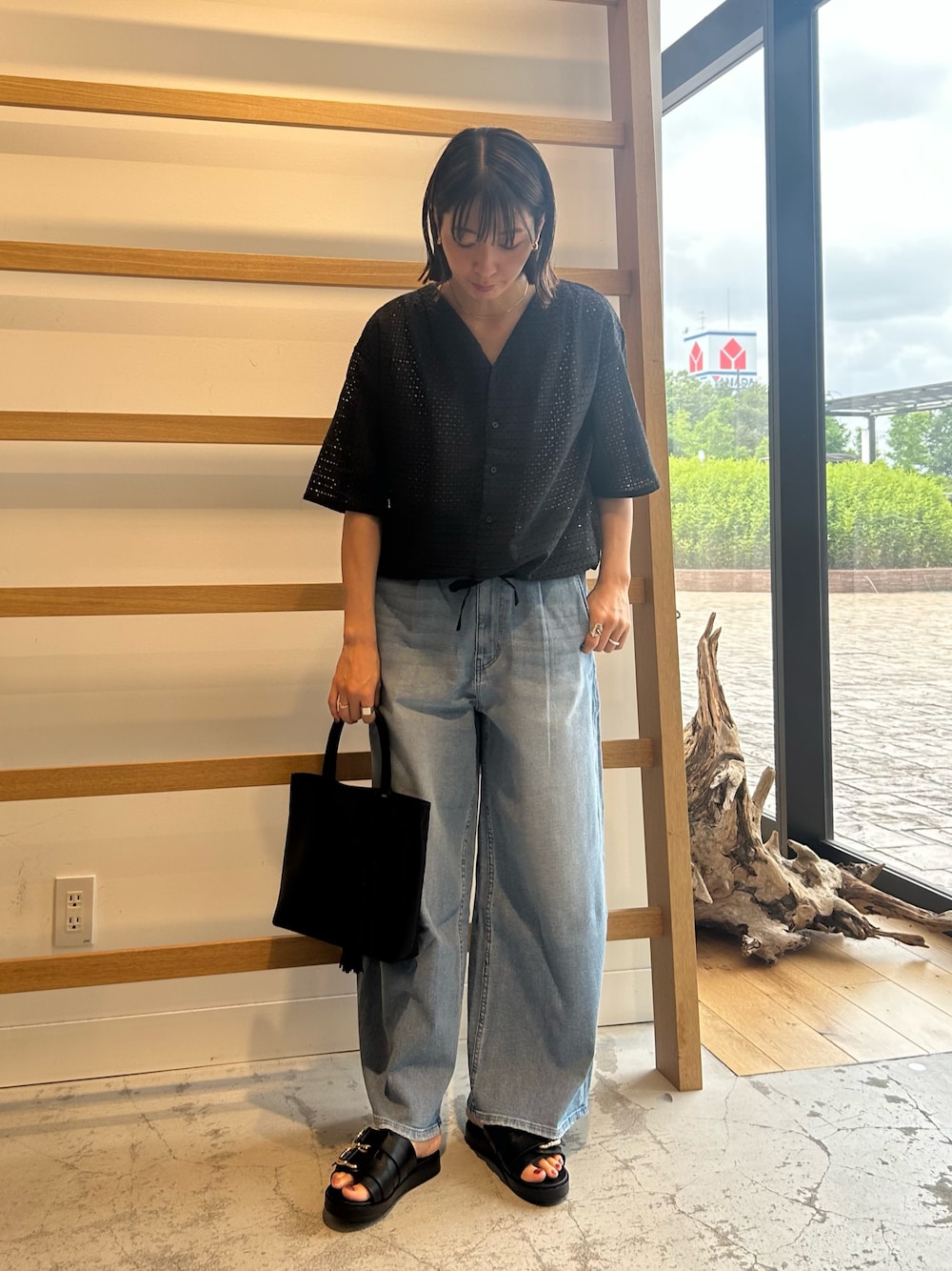 ブルー系のデニムパンツ、ブラック系のトートバッグ、ブラック系のサンダルを着用したレディースの夏コーディネートの1枚目の写真