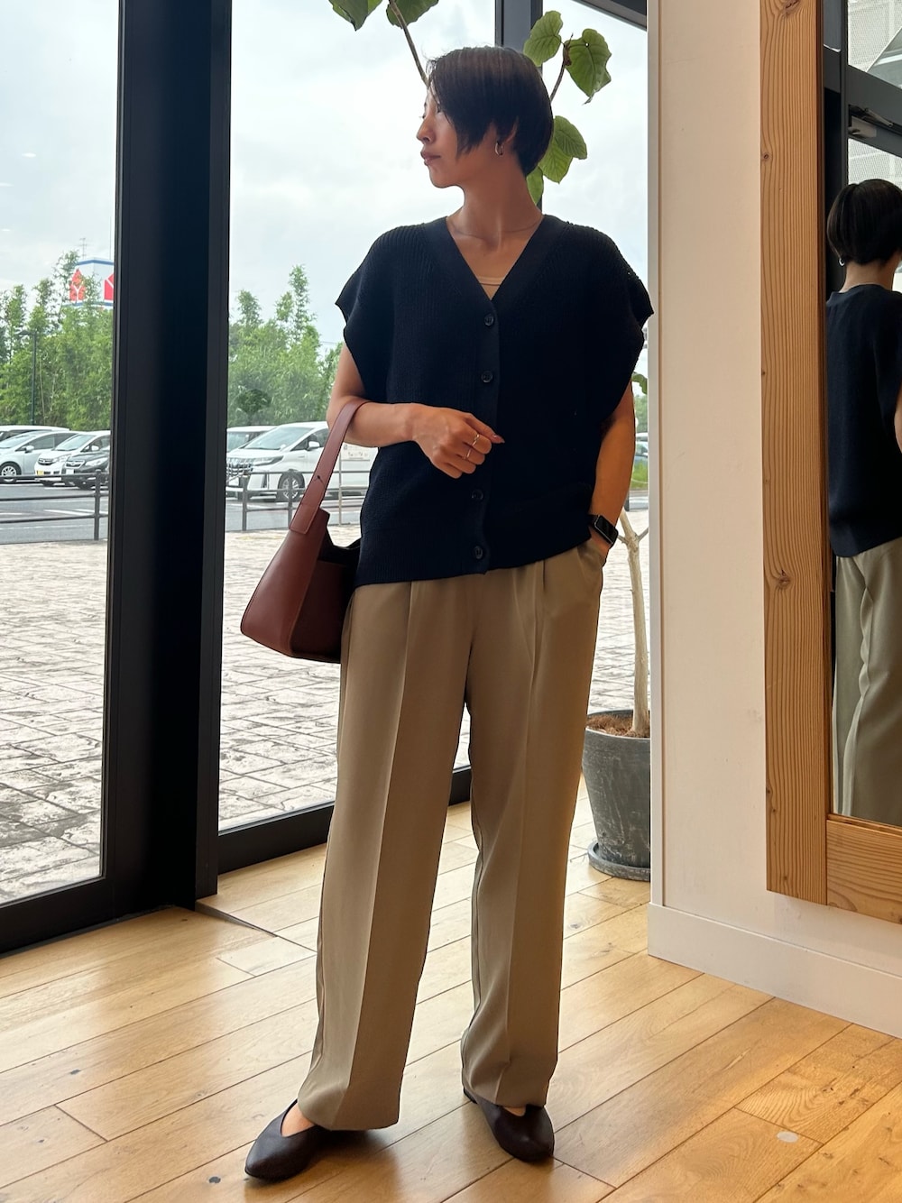 ブルー系のベスト、ブラウン系のハンドバッグ、ベージュ系のその他パンツを着用したレディースの秋コーディネートの1枚目の写真