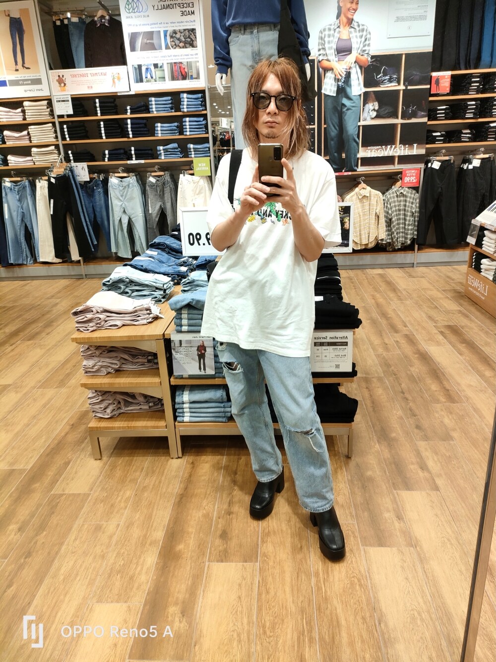 ホワイト系のTシャツ/カットソー、ブルー系のデニムパンツ、ブラック系のブーツを着用したメンズの冬コーディネートの1枚目の写真