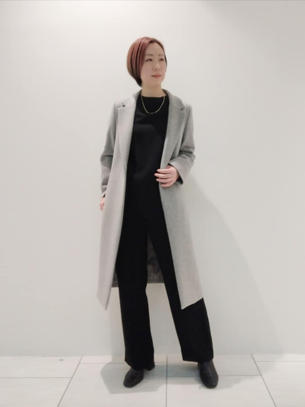 グレー系のチェスターコート、ブラック系のシャツ/ブラウス、ブラック系のスーツパンツを着用したレディースの冬コーディネートの1枚目の写真
