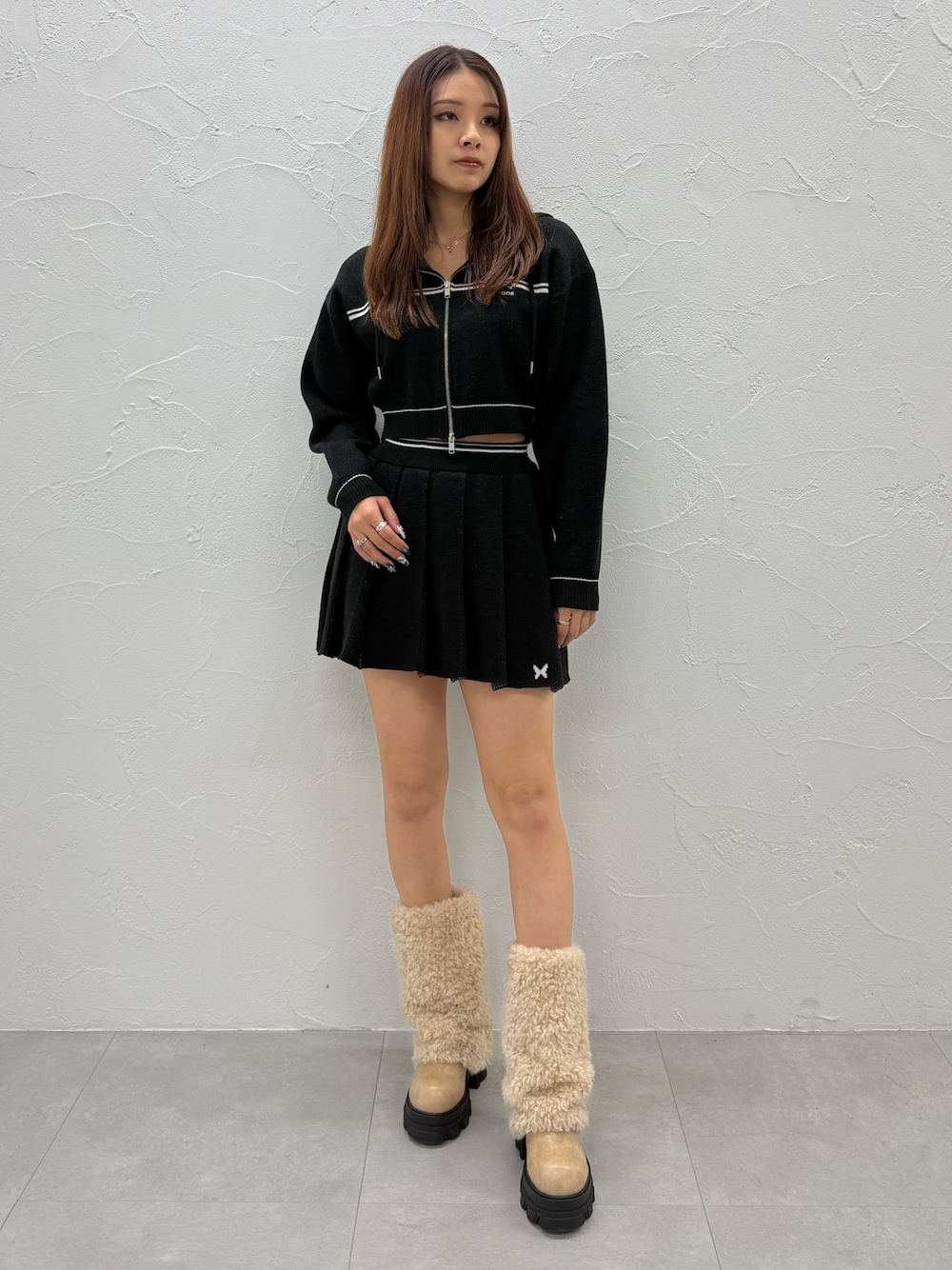 ブラック系のスカート、ホワイト系のブーツ、ブラック系のニット/セーターを着用したレディースの冬コーディネートの1枚目の写真