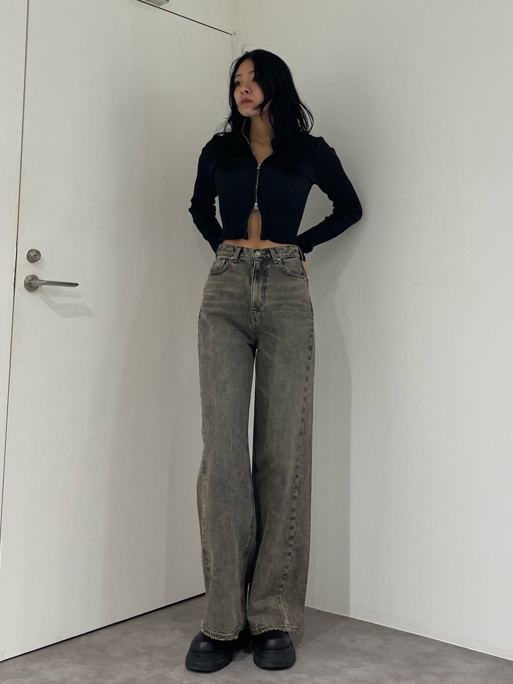 ブラック系のニット/セーター、グレー系のデニムパンツ、ブラック系のブーツを着用したレディースの春コーディネートの1枚目の写真