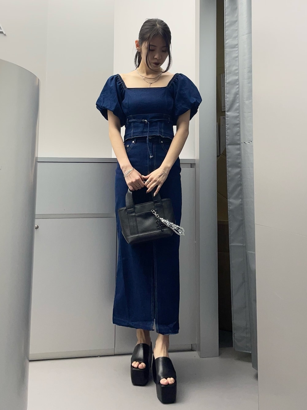 ブルー系のシャツ/ブラウス、ブルー系のスカート、ブラック系のハンドバッグを着用したレディースの春コーディネートの1枚目の写真