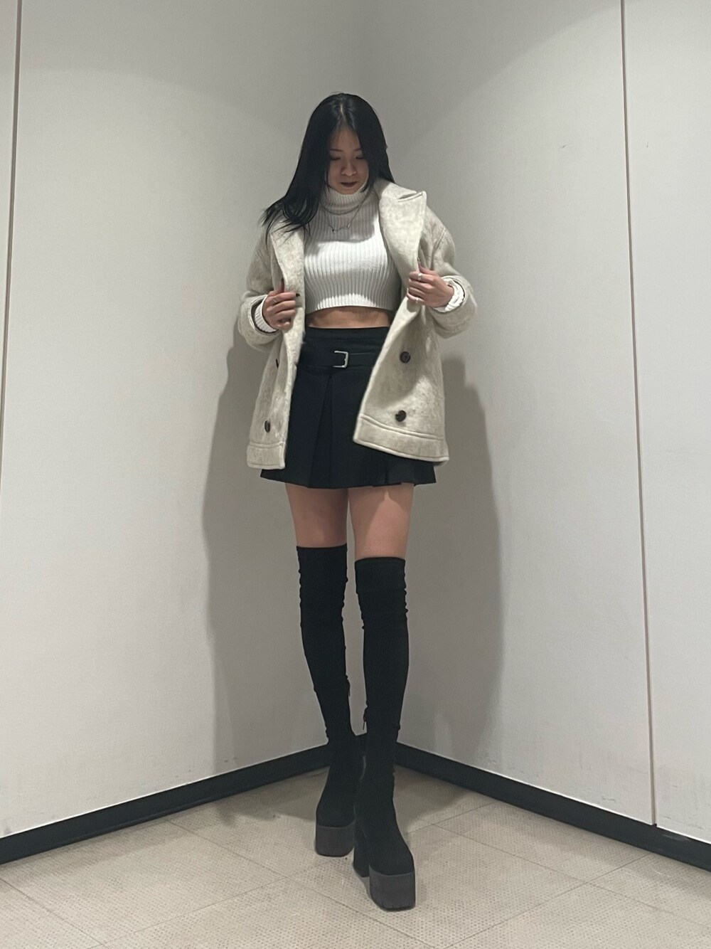 ホワイト系のニット/セーター、ホワイト系のピーコート、ブラック系のスカートを着用したレディースの冬コーディネートの1枚目の写真