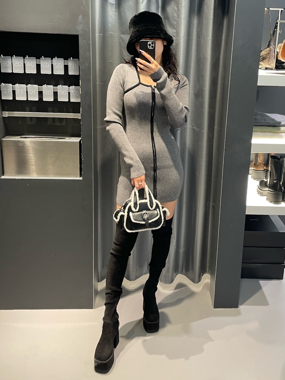 グレー系のワンピース、ブラック系のハンドバッグ、ブラック系のブーツを着用したレディースの冬コーディネートの1枚目の写真