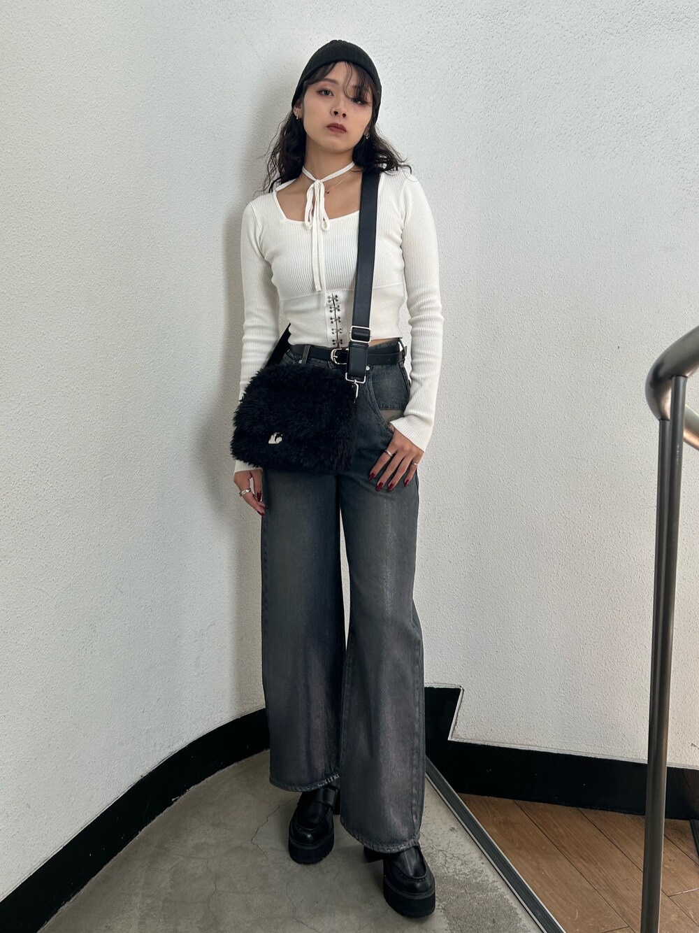 ホワイト系のニット/セーター、ブラック系のハンドバッグ、ブルー系のデニムパンツを着用したレディースの秋コーディネートの1枚目の写真