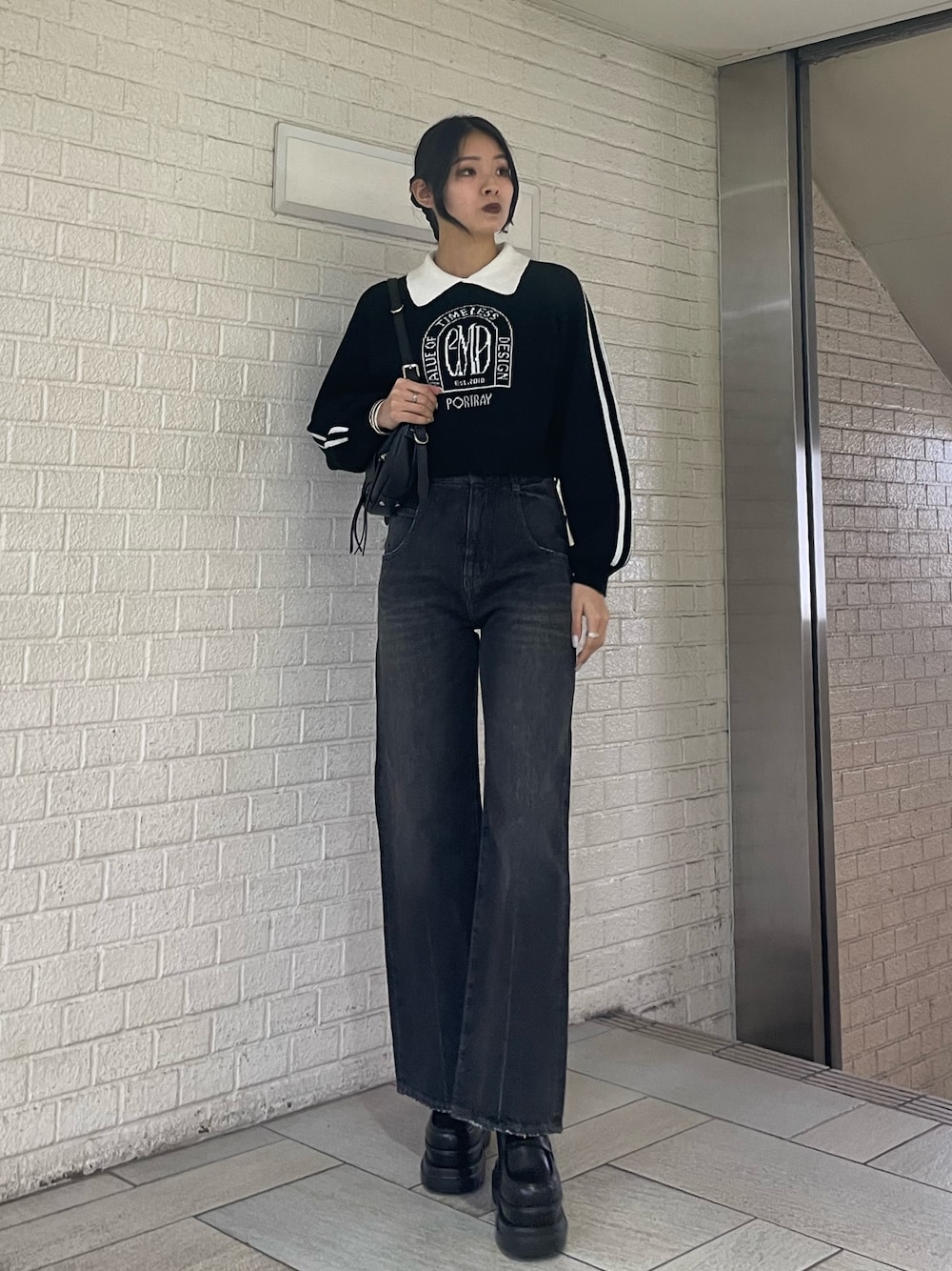 ブラック系のニット/セーター、ブラック系のハンドバッグ、ブラック系のデニムパンツを着用したレディースの冬コーディネートの1枚目の写真