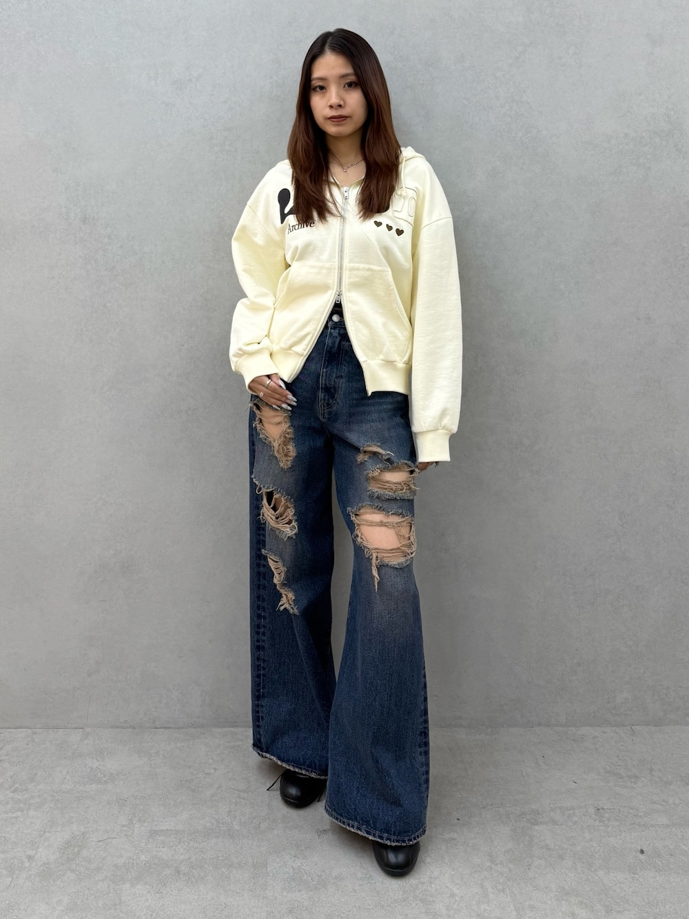 ホワイト系のパーカー、ブルー系のデニムパンツ、ブラック系のパンプスを着用したレディースの冬コーディネートの1枚目の写真