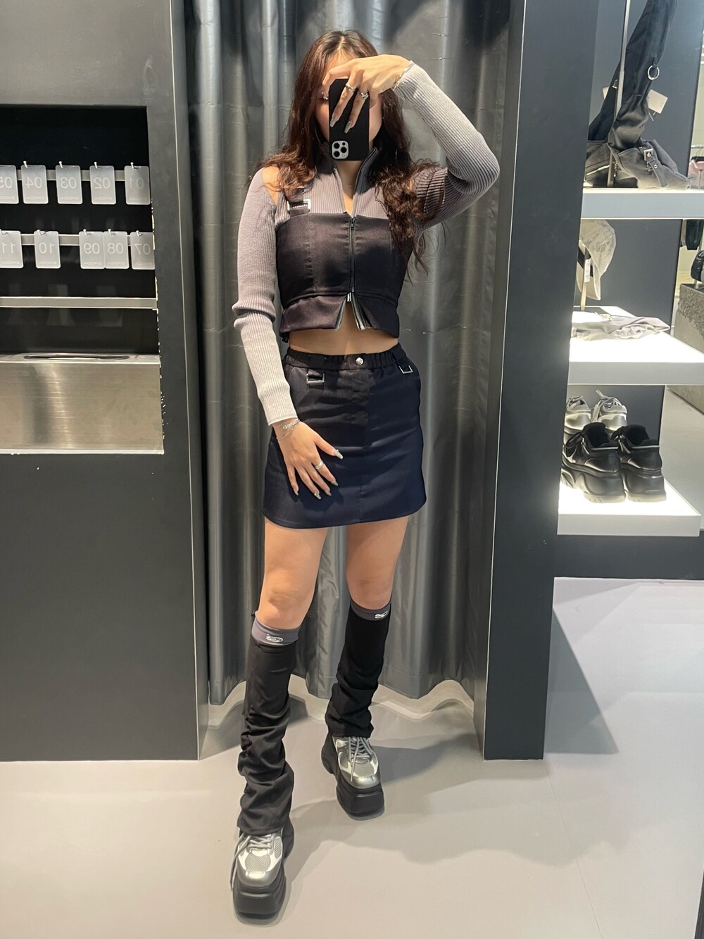 グレー系のニット/セーター、ブルー系のスカート、シルバー系のスニーカーを着用したレディースの冬コーディネートの1枚目の写真