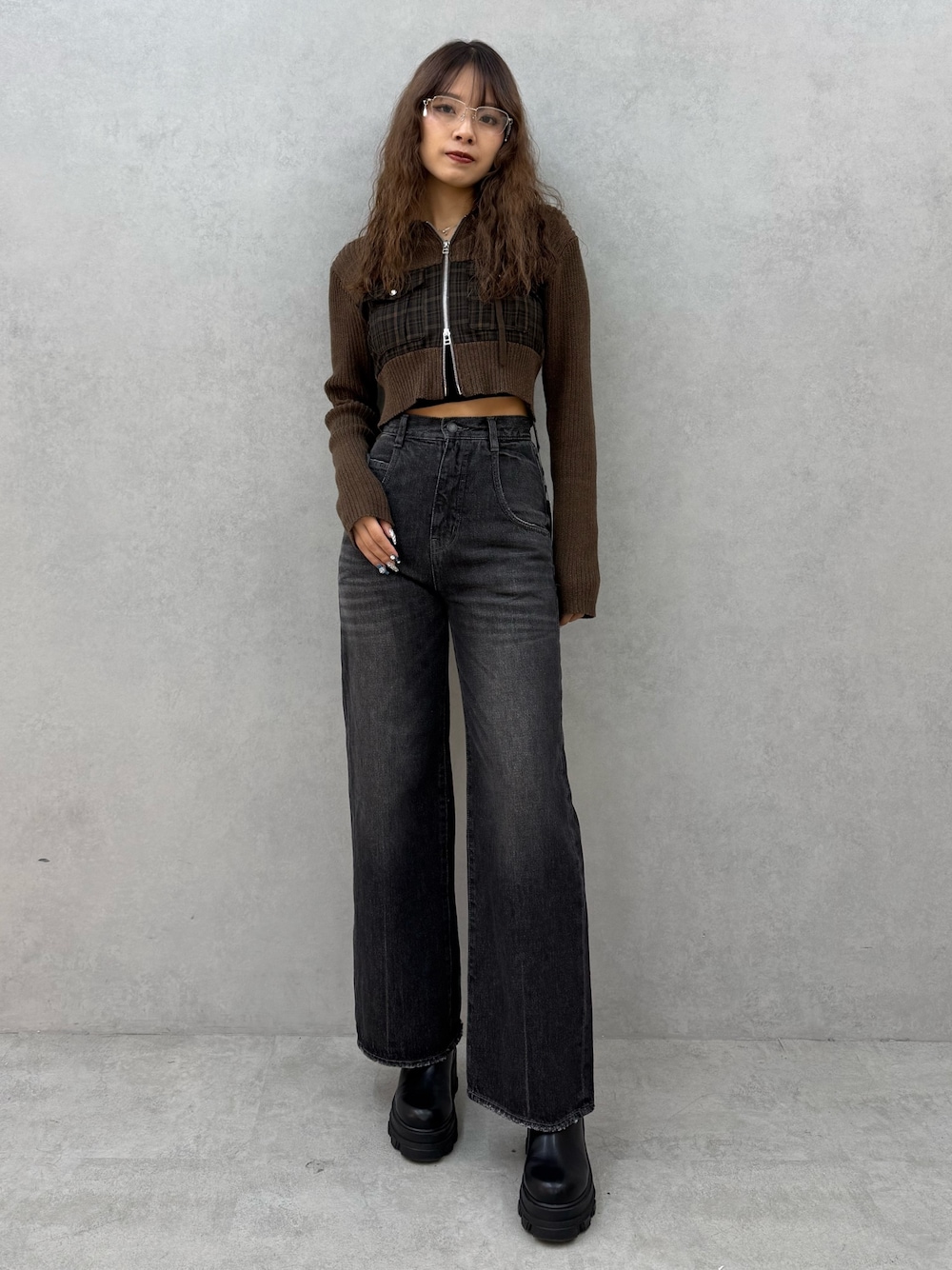 グリーン系のニット/セーター、ブラック系のデニムパンツ、ブラック系のブーツを着用したレディースの秋コーディネートの1枚目の写真