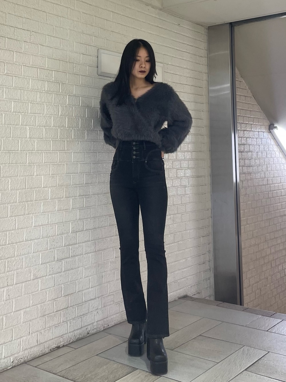 グレー系のニット/セーター、ブラック系のデニムパンツ、ブラック系のブーツを着用したレディースの冬コーディネートの1枚目の写真
