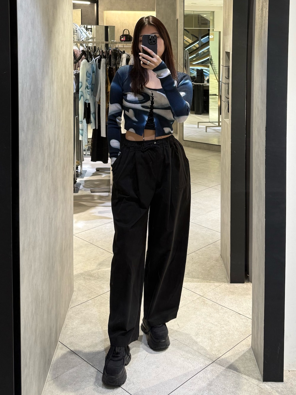 ブラック系のスニーカー、ブラック系のその他パンツ、ブルー系のニット/セーターを着用したレディースの春コーディネートの1枚目の写真