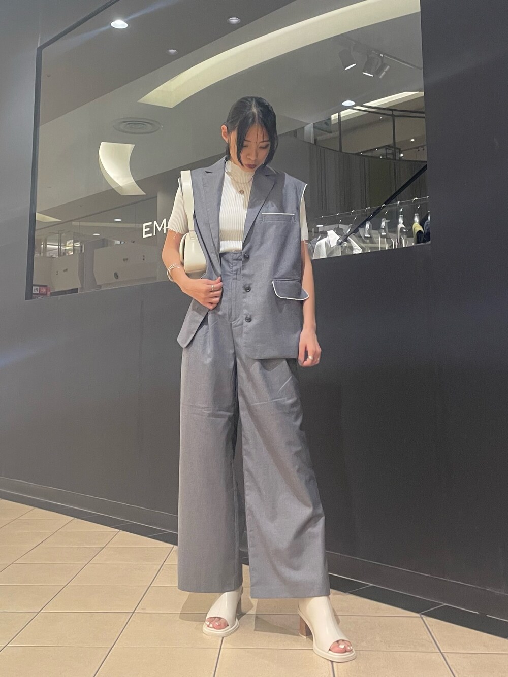 ホワイト系のニット/セーター、ホワイト系のハンドバッグ、グレー系のベストを着用したレディースの夏コーディネートの1枚目の写真