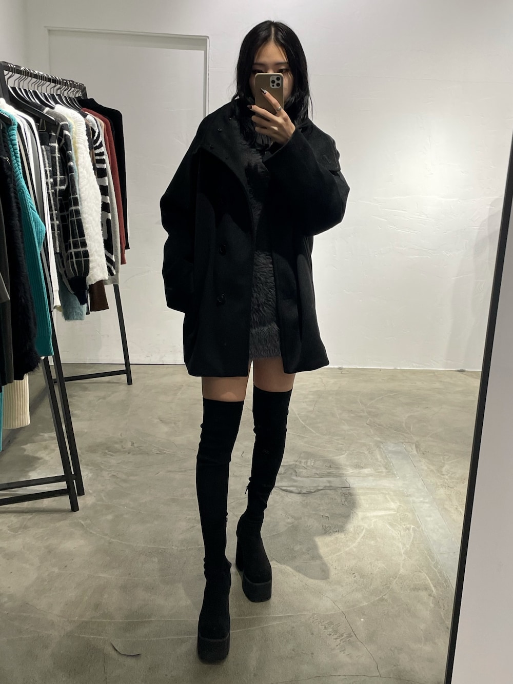 ブラック系のピーコート、グレー系のワンピース、ブラック系のブーツを着用したレディースの冬コーディネートの1枚目の写真