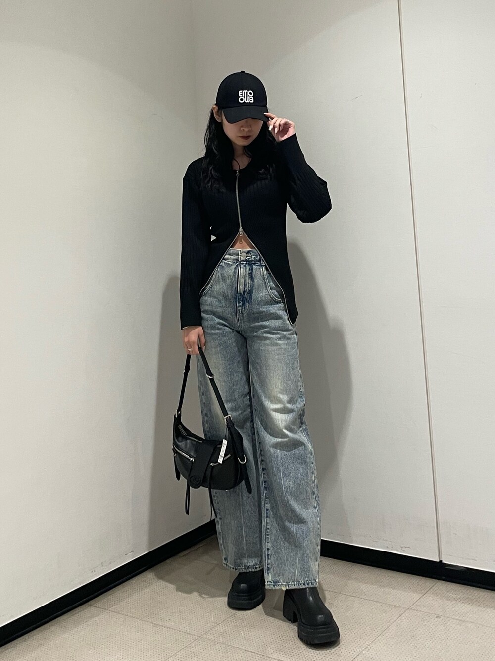 ブラック系のニット/セーター、ブルー系のデニムパンツ、ブラック系のハンドバッグを着用したレディースの冬コーディネートの1枚目の写真