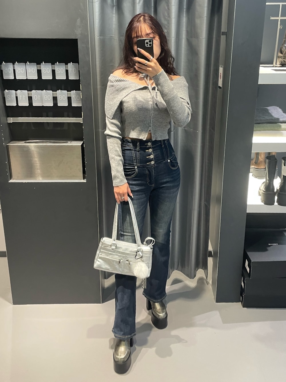 グレー系のニット/セーター、ブルー系のデニムパンツ、シルバー系のショルダーバッグを着用したレディースの冬コーディネートの1枚目の写真