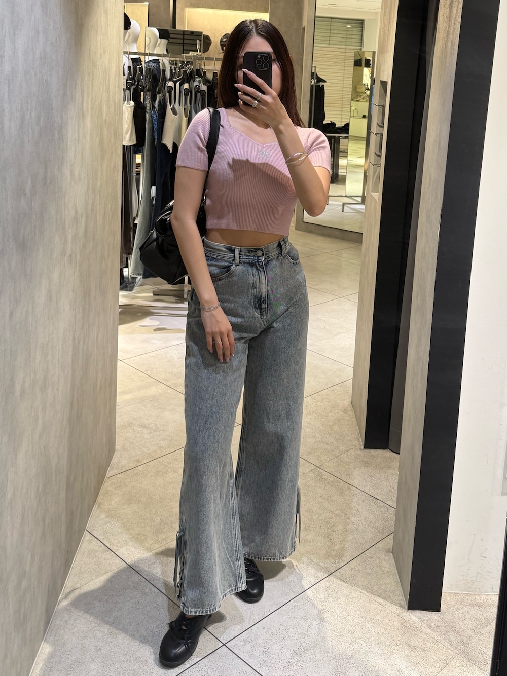 ピンク系のニット/セーター、ブラック系のトートバッグ、ブルー系のデニムパンツを着用したレディースの春コーディネートの1枚目の写真