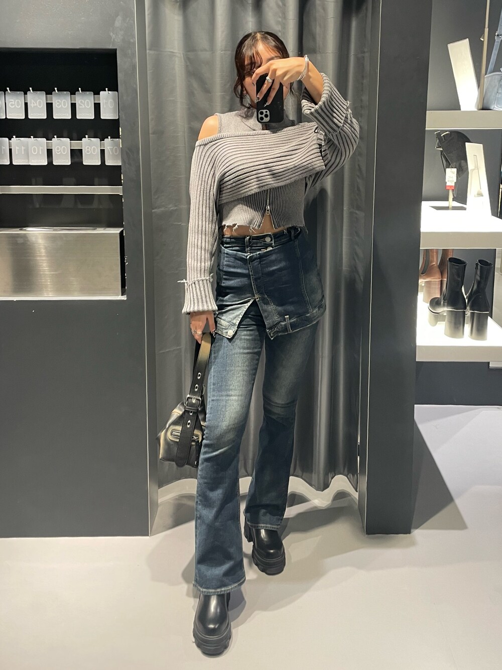 グレー系のニット/セーター、ブルー系のデニムパンツ、ブラック系のハンドバッグを着用したレディースの秋コーディネートの1枚目の写真