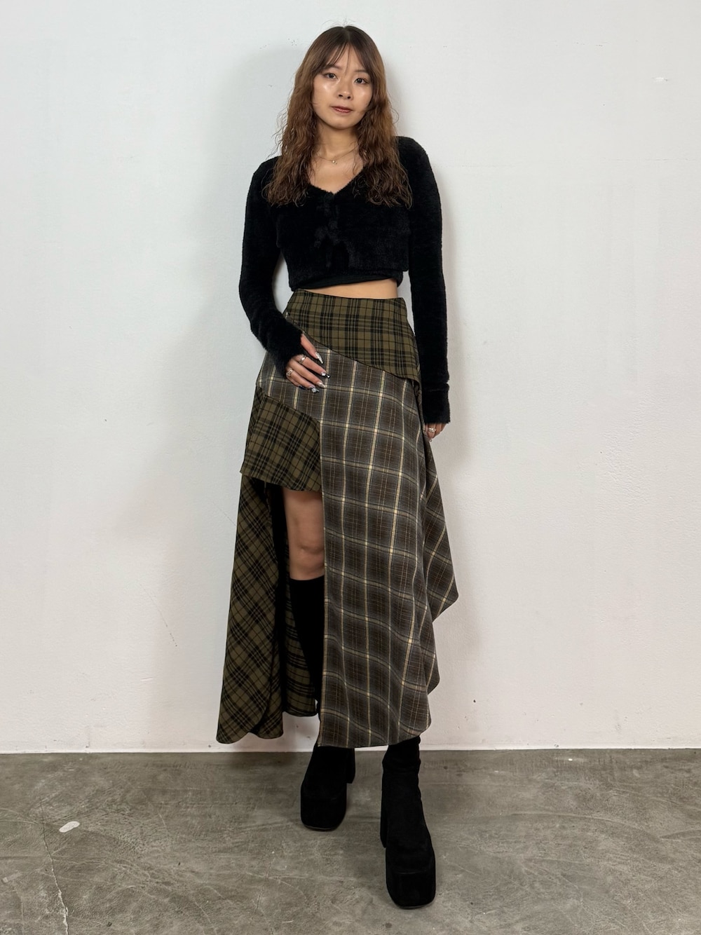 ブラック系のニット/セーター、グリーン系のスカート、ブラック系のブーツを着用したレディースの秋コーディネートの1枚目の写真