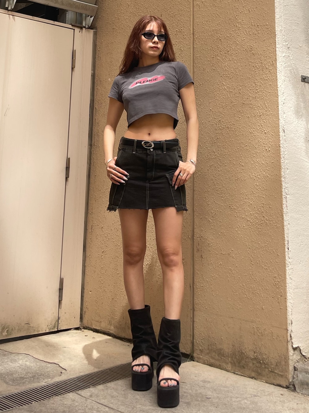 グレー系のTシャツ/カットソー、ブラック系のスカート、ブラック系のサンダルを着用したレディースの春コーディネートの1枚目の写真