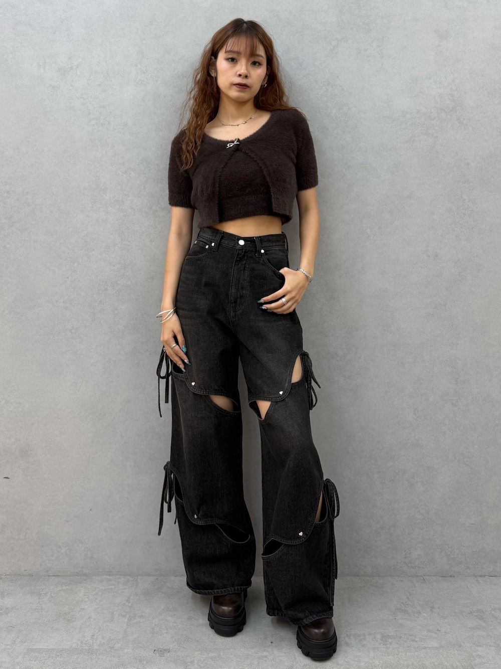 ブラウン系のニット/セーター、ブラック系のデニムパンツ、ブラウン系のブーツを着用したレディースの夏コーディネートの1枚目の写真