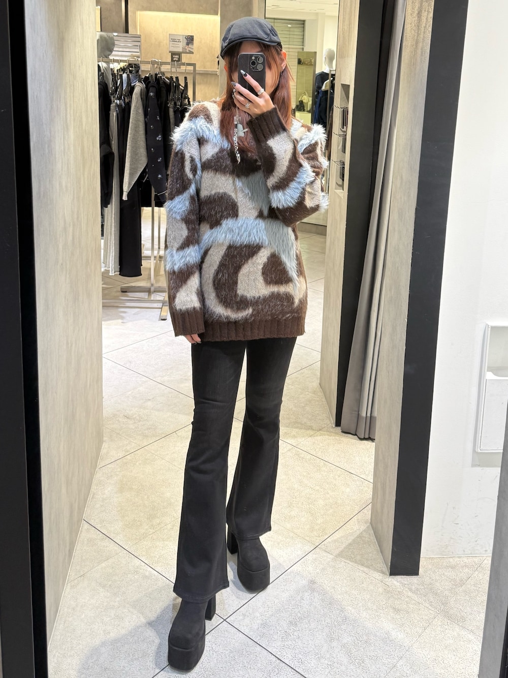 ブラウン系のニット/セーター、ブラック系のデニムパンツ、ブラック系のブーツを着用したレディースの秋コーディネートの1枚目の写真