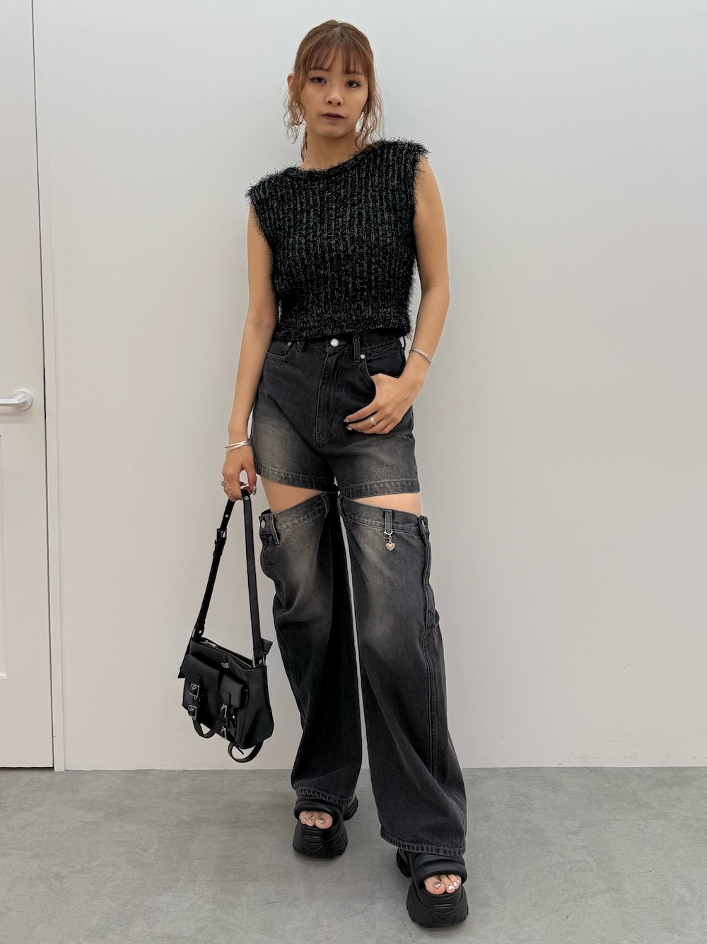 ブラック系のニット/セーター、ブラック系のデニムパンツ、ブラック系のハンドバッグを着用したレディースの夏コーディネートの1枚目の写真