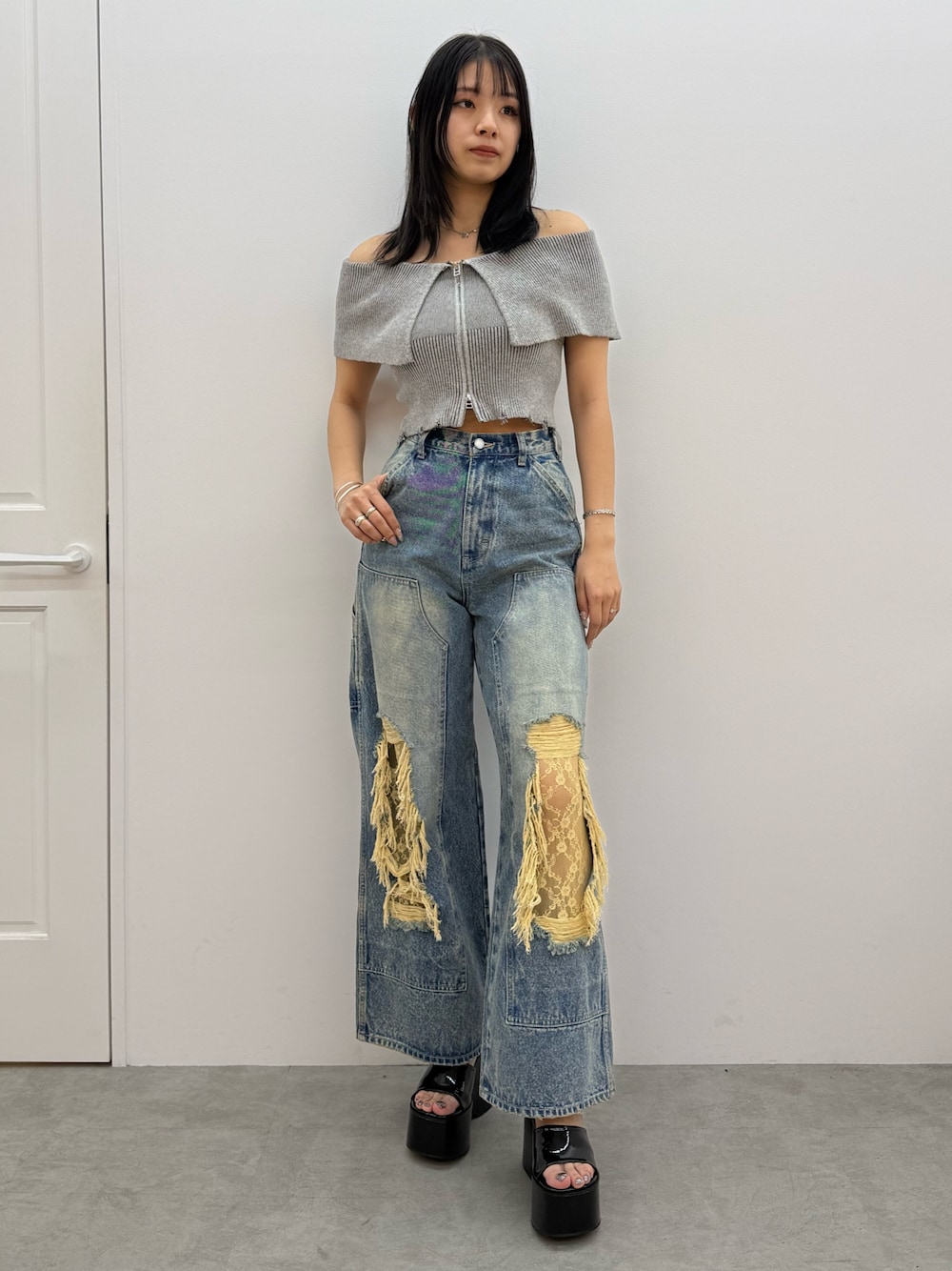 グレー系のニット/セーター、ブルー系のデニムパンツ、ブラック系のサンダルを着用したレディースの春コーディネートの1枚目の写真