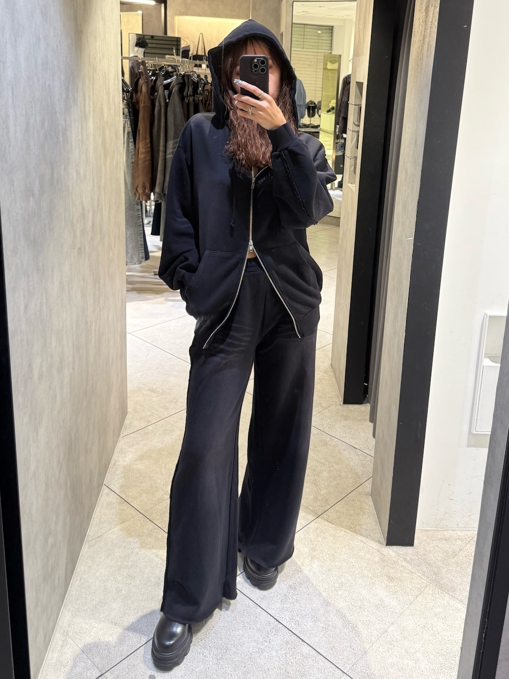 ブラック系のパーカー、ブラック系のスウェットパンツ、ブラック系のブーツを着用したレディースの秋コーディネートの1枚目の写真