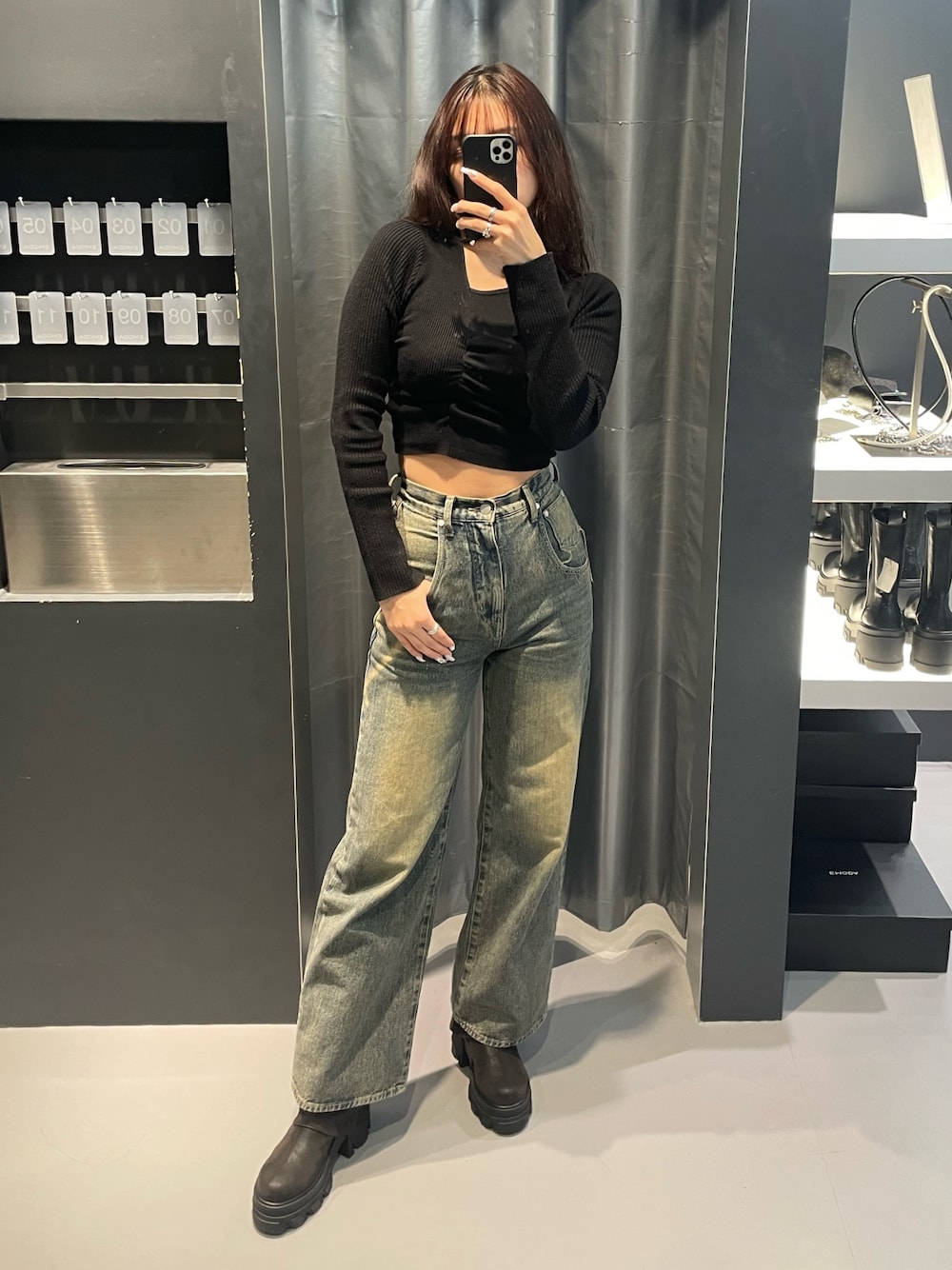 ブラック系のニット/セーター、ブルー系のデニムパンツ、ブラック系のブーツを着用したレディースの冬コーディネートの1枚目の写真