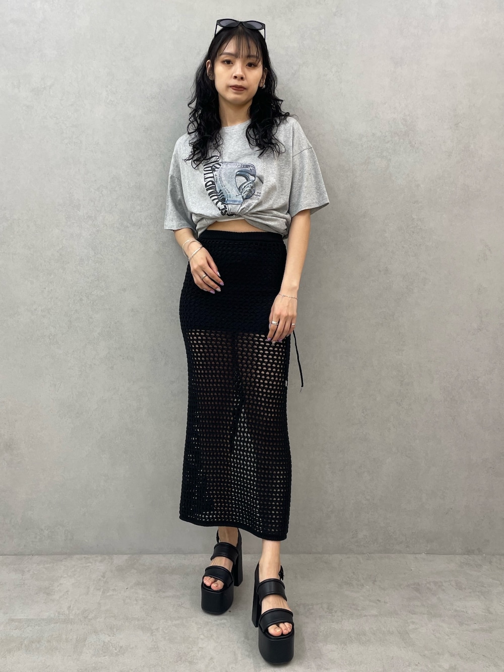 グレー系のTシャツ/カットソー、ブラック系のスカート、ブラック系のサンダルを着用したレディースの春コーディネートの1枚目の写真