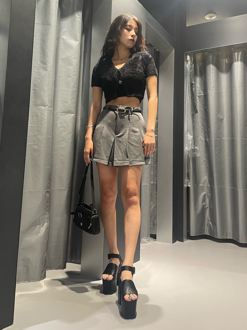 ブラック系のニット/セーター、グレー系のスカート、ブラック系のショルダーバッグを着用したレディースの夏コーディネートの1枚目の写真