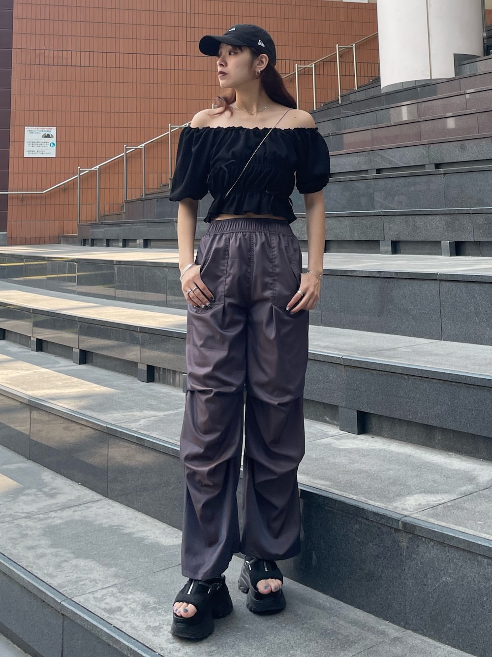 ブラック系のハンドバッグ、ブラック系のTシャツ/カットソー、ブラウン系のその他パンツを着用したレディースの春コーディネートの1枚目の写真