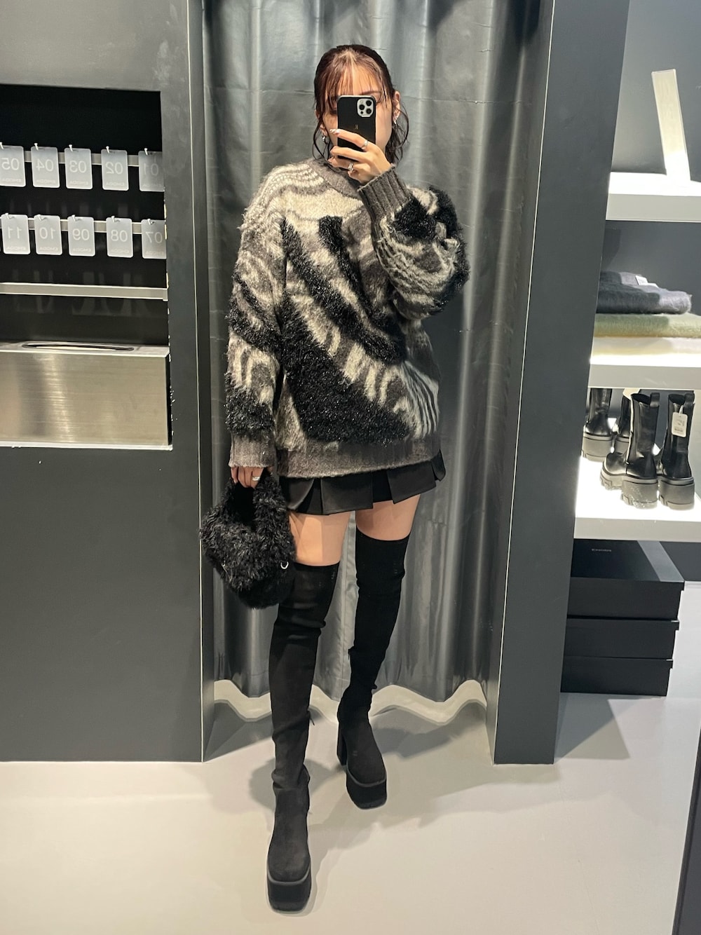 グレー系のニット/セーター、ブラック系のスカート、ブラック系のハンドバッグを着用したレディースの冬コーディネートの1枚目の写真